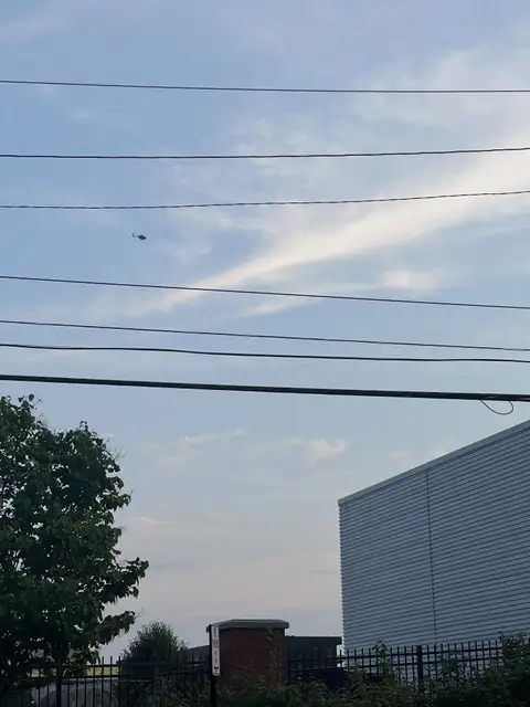 Urban sky meets power lines and distant flight.